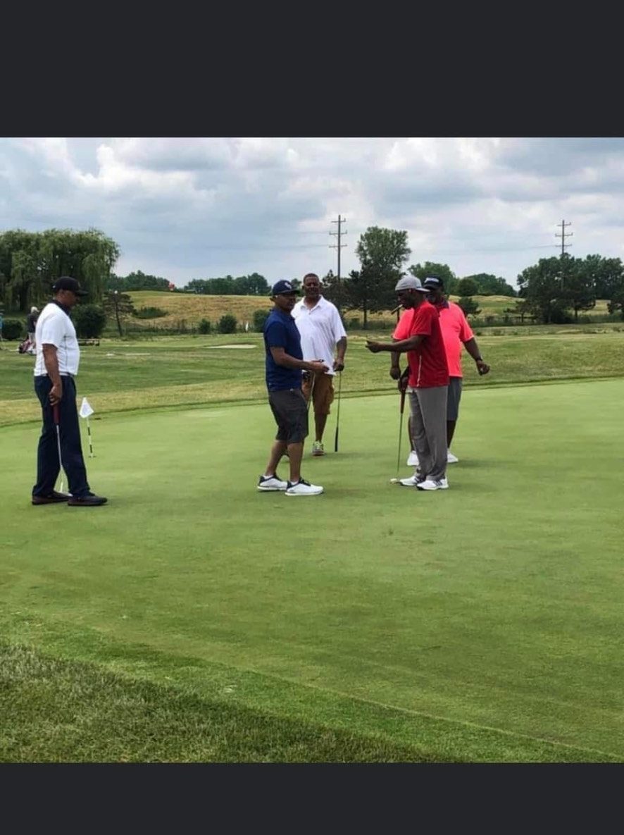 Friends gathered on a putting green reading a putt under summer sky