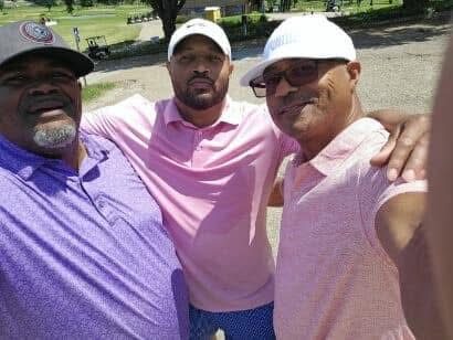 Three friends in pink and grey polos posing on the course